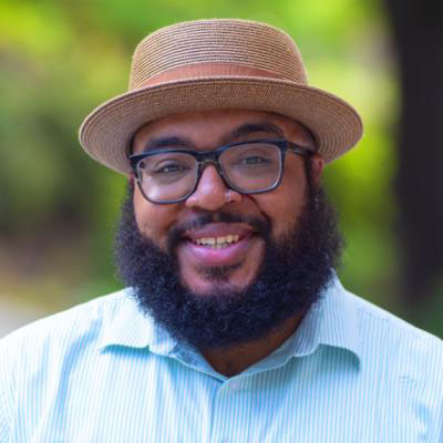 Un hombre negro que lleva un sombrero porkpie dorado.