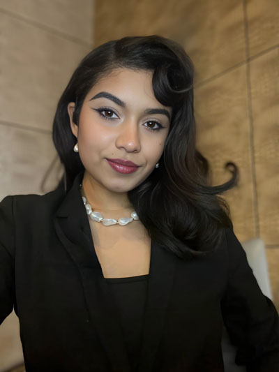 Una mujer puertorriqueña morena con cabello oscuro y blazer negro.